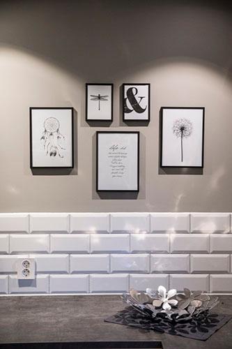 White brick-pattern wall tiles behind a worktop, with framed prints above